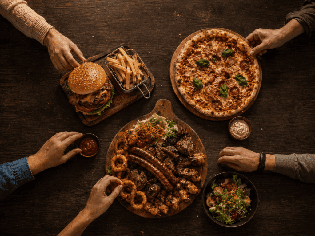 Hrana na stolu. Burger, pomfrit, pizza i miješana plata.