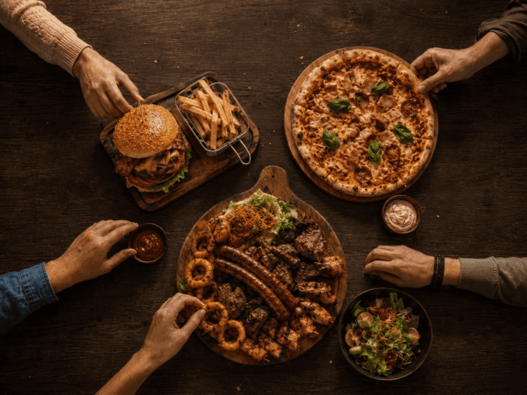 Hrana na stolu. Burger, pomfrit, pizza i miješana plata.